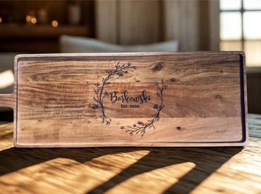 Wooden cutting board with a floral engraved design and family name.