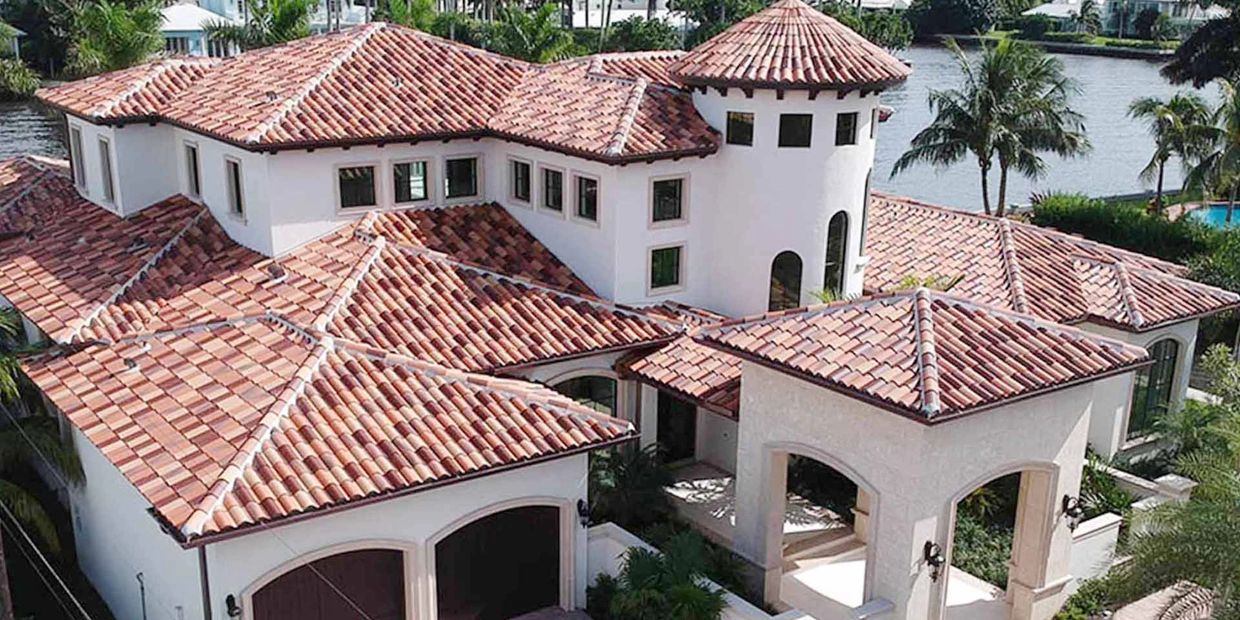 A large Mediterranean-style house with terracotta tiled roofs and a waterfront view.