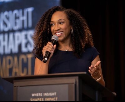 Woman speaking confidently at a podium with a microphone.