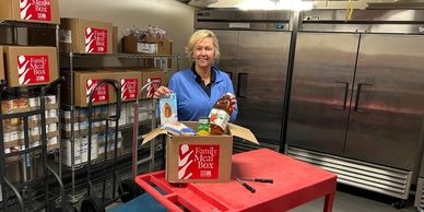 Volunteer packing food items in a Family Meal Box.