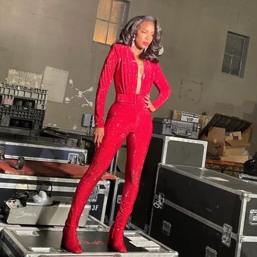 Woman in a sparkling red jumpsuit posing.