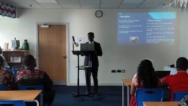 A person giving a presentation to an audience in a classroom.
