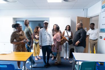 A diverse group of adults standing and talking in a classroom.