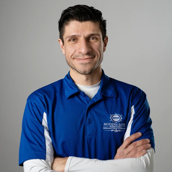 Man in blue work shirt smiling with arms crossed.