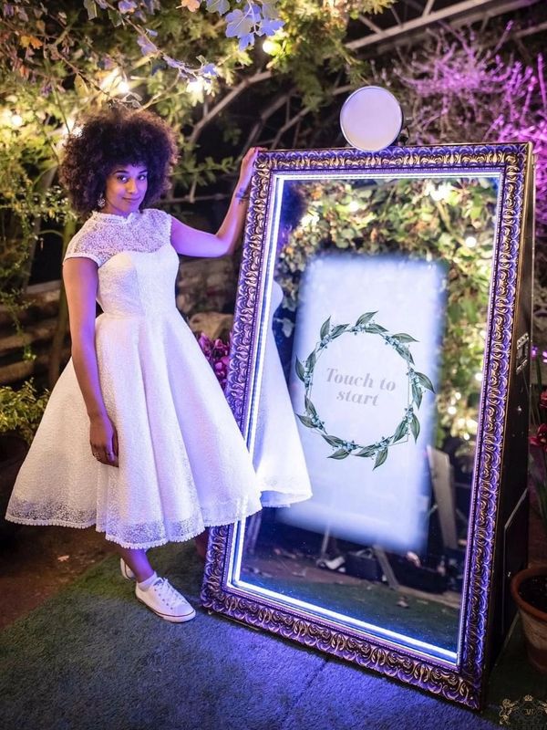 Beautiful girl with a white dress and converses standing in front luxury photobooth 