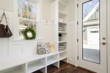 Bright and cozy mudroom with white shelves and bench.