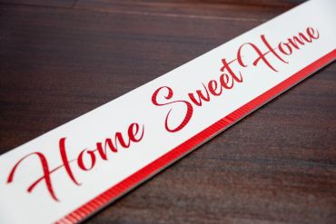A decorative sign with 'Home Sweet Home' in red script on white.