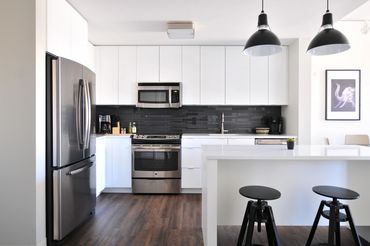 Modern kitchen with white cabinets and stainless steel appliances.