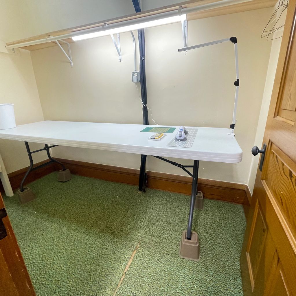 A work table with crafting tools and bright lighting in a small room.