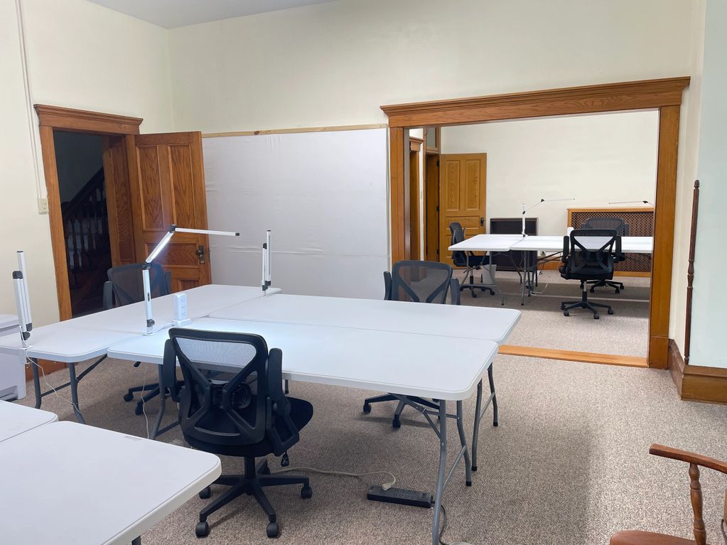 Modern office with white tables, black chairs, and a large wall mirror.