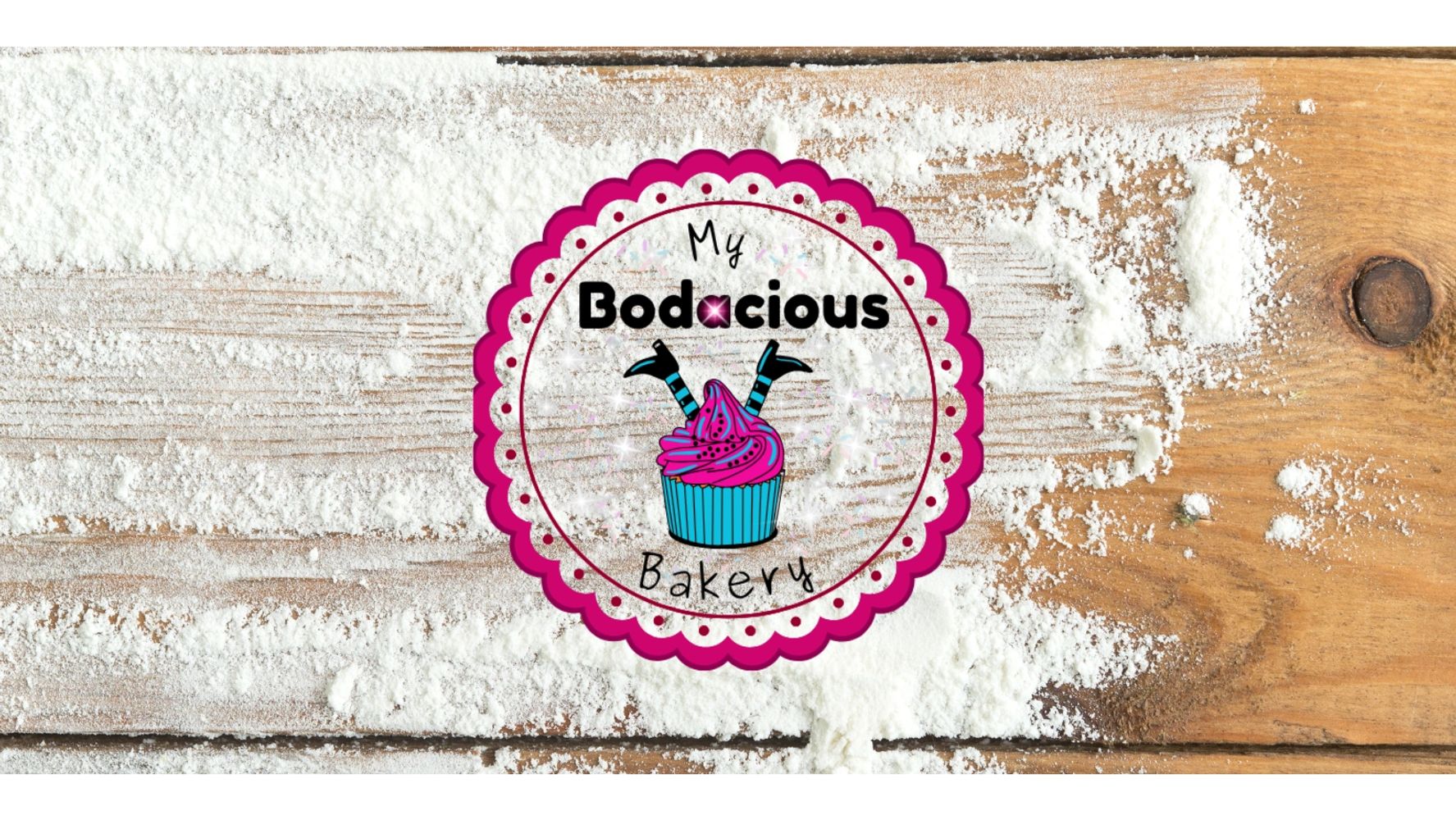 Logo of My Bodacious Bakery with a cupcake on a flour-dusted wooden surface.