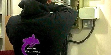 Person wearing a Gecko Electrical jacket working on an electrical box.