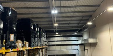 Warehouse interior with stacked pallets and ceiling lights.