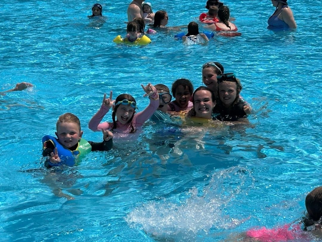 A group of children happily swimming in a pool.