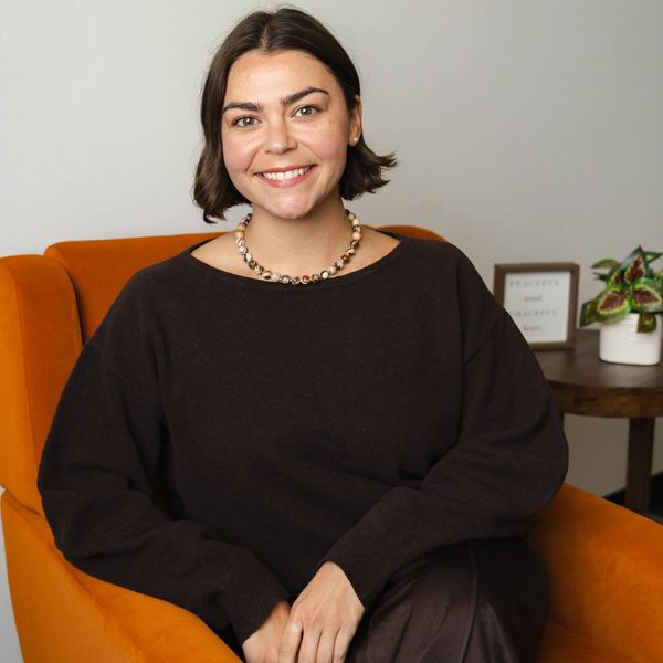 Smiling woman sitting in an orange chair.
