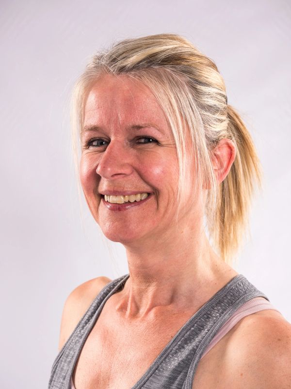 Smiling middle-aged woman with blonde hair in a ponytail.