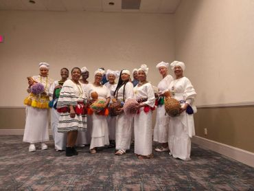 Group of women dressed in traditional white attire holding decorated gourds.