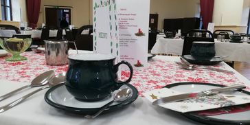 Festive holiday table setting with menu and dark ceramic mugs.