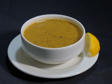 Kase içinde mercimek çorbası ve yanında limon dilimi.