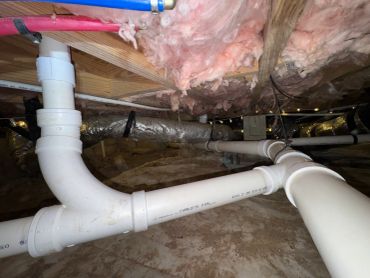 PVC plumbing pipes under a house crawl space.