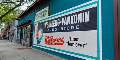 Vintage drug store mural advertising Williams Ice Cream on a city sidewalk.