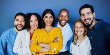 A group of six diverse friends smiling together against a blue background.