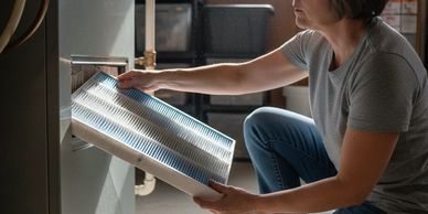 Woman replacing an air filter in a furnace.