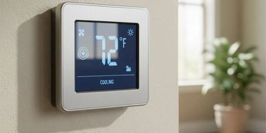 Modern thermostat displaying 72°F and cooling mode on a beige wall.
