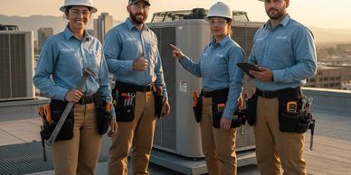 Four HVAC technicians in uniform standing on a rooftop with tools and equipment.