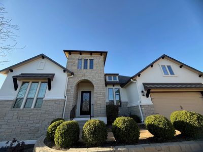 Modern house with stone and white walls under a clear blue sky.
