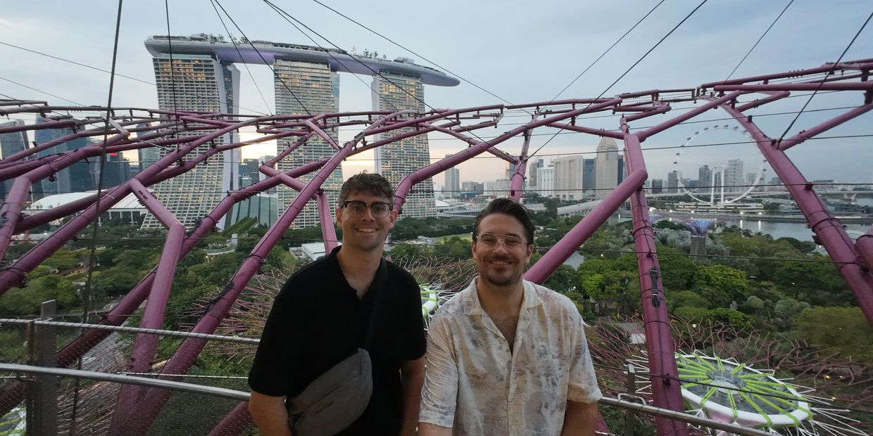 Two men smiling with Singapore's Marina Bay Sands in the background.