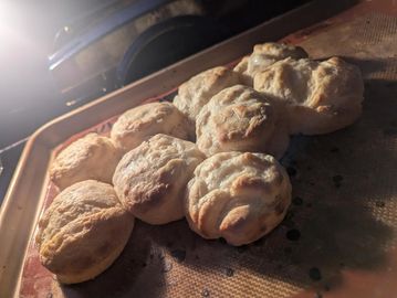 Freshly baked golden biscuits on a baking tray.