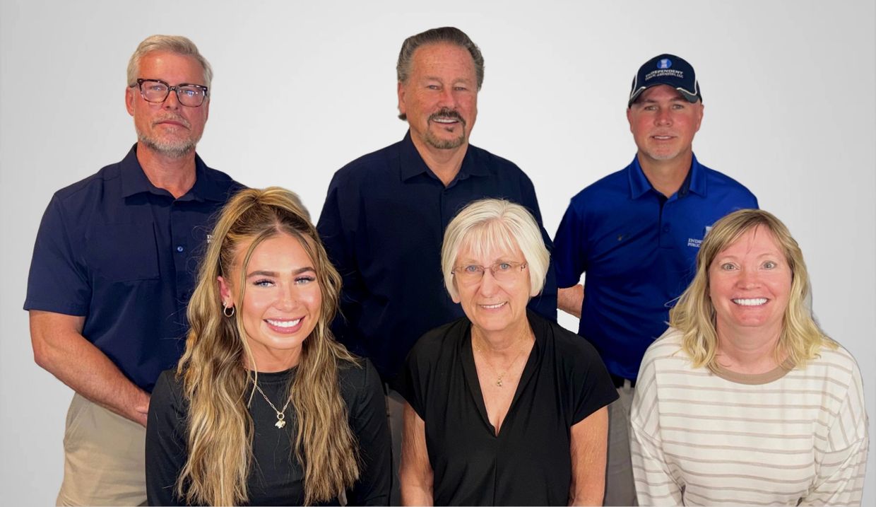 Group photo of six smiling adults against a plain background.