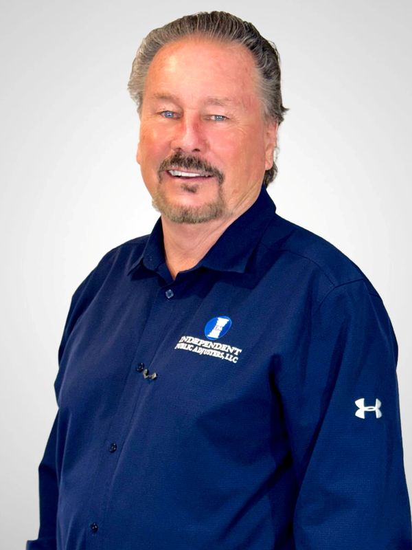 Man in a navy blue shirt with company logo smiles at the camera.
