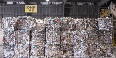 Fardos de papel compactado em armazém industrial.