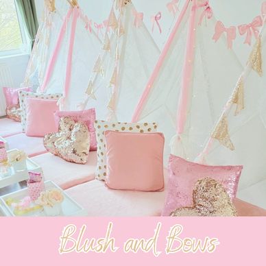 A pastel pink and gold themed kids' party setup with tents and cushions.