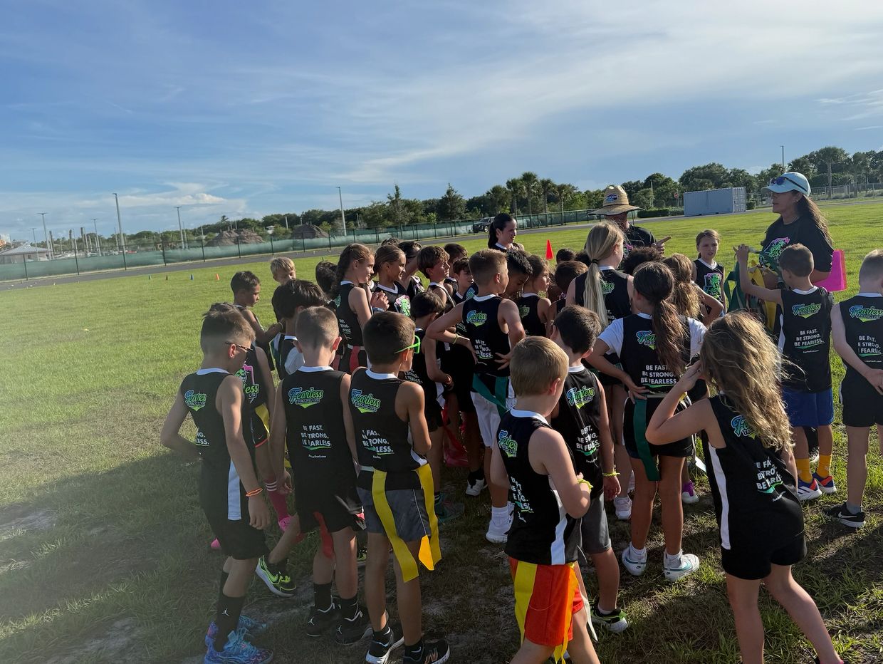 Youth flag football team gathers on the field for instructions.
