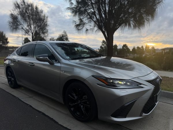 Silver luxury sedan parked on the street at sunset.