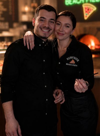 Two smiling restaurant employees posing together in matching black uniforms.