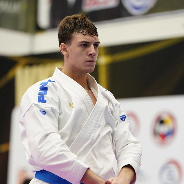 Focused martial artist wearing a white gi and blue belt.