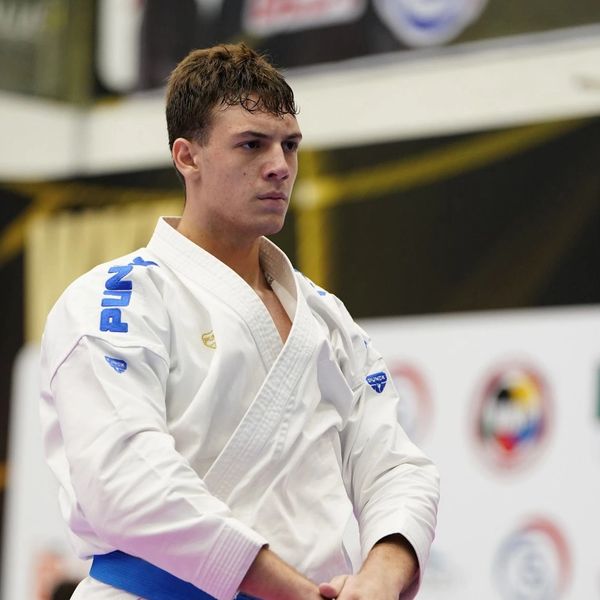 Focused martial artist wearing a white gi and blue belt.