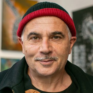 Middle-aged man wearing a red and black beanie, smiling gently.