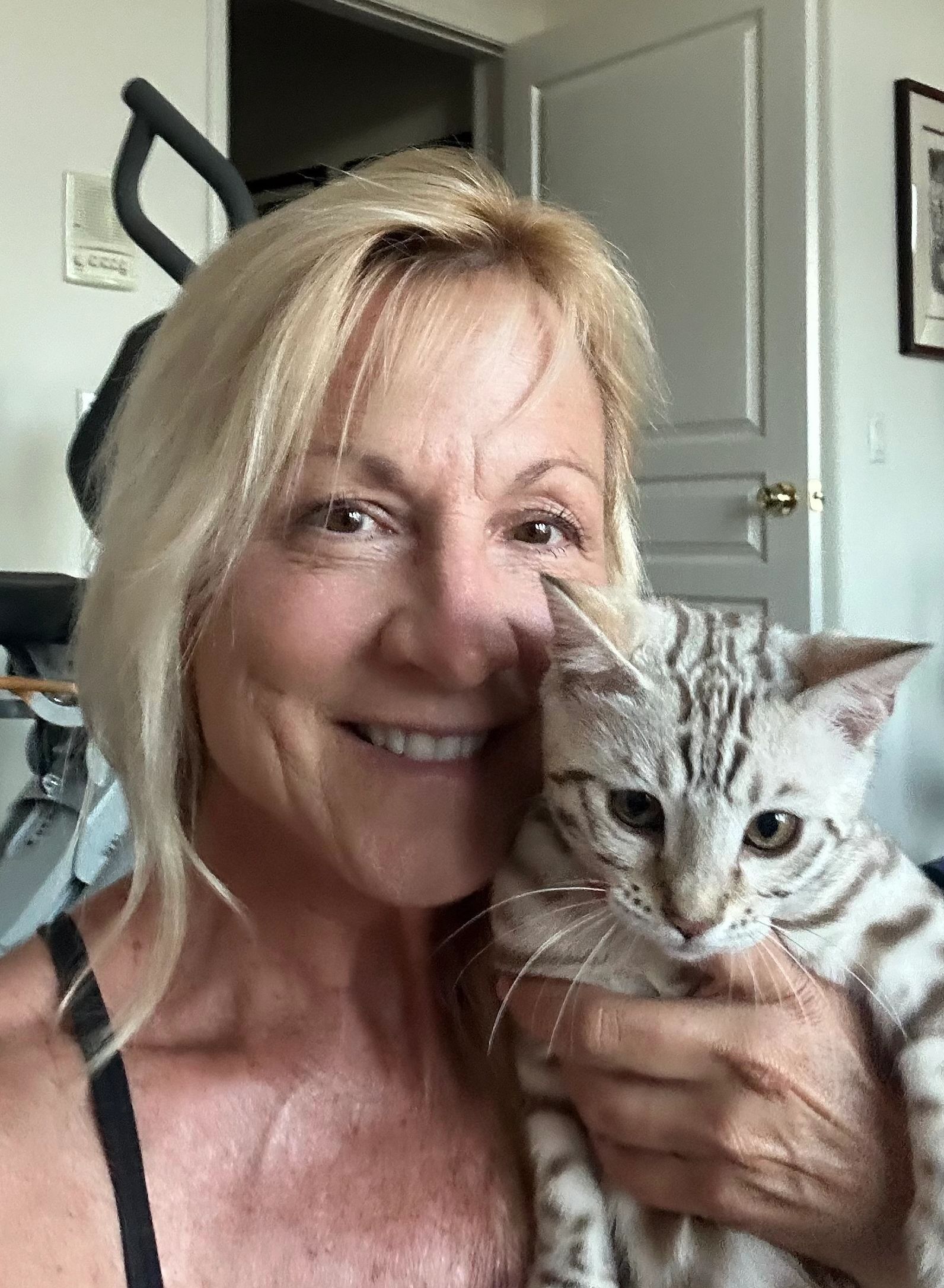 Smiling woman holding a spotted cat.