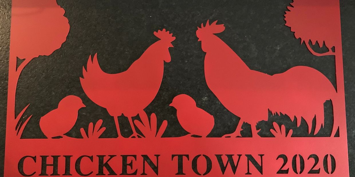 A metal cutout sign with a chicken, rooster, 2 chicks and 2 trees, the words "Chicken Town 2020".