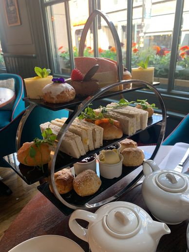 Elegant three-tier afternoon tea set with sandwiches, pastries, and tea pots.