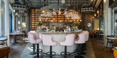 Elegant bar with plush pink stools and warm lighting.