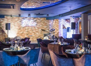 Upscale dining area with modern seating and a drum set on stage.