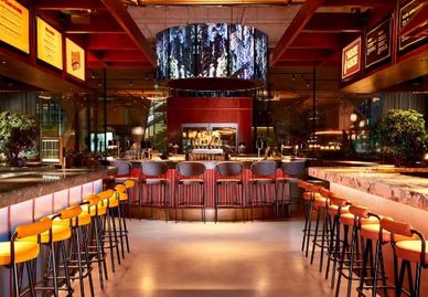 Modern bar with orange stools and ambient lighting.