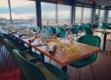 Elegant restaurant with green chairs and scenic waterfront views.