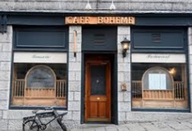 Exterior of Café Boheme with wooden door and bicycle outside.